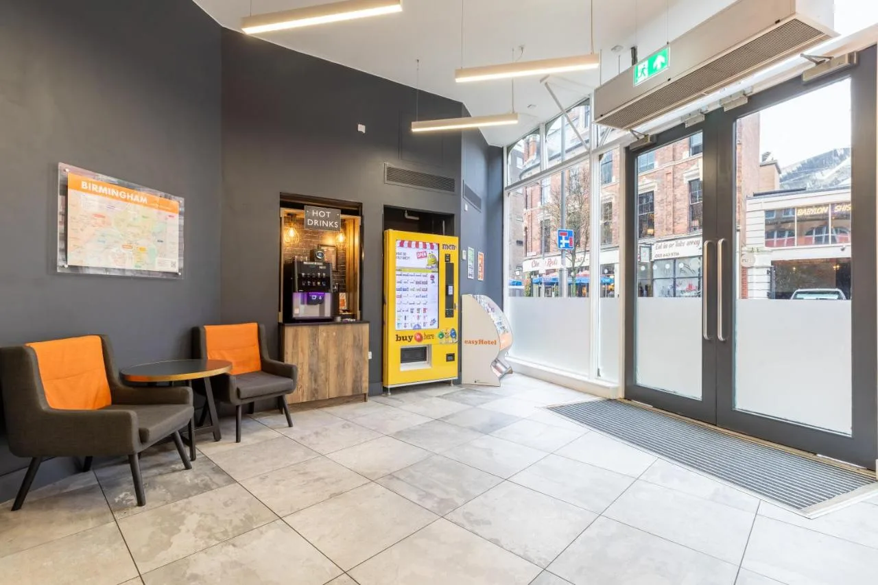 Waiting room with orange chairs and a table at easyHotel Birmingham